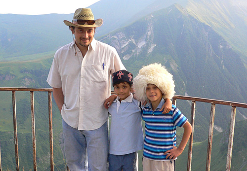 Levan Vasadze 95MBA with two children in front of mountains.