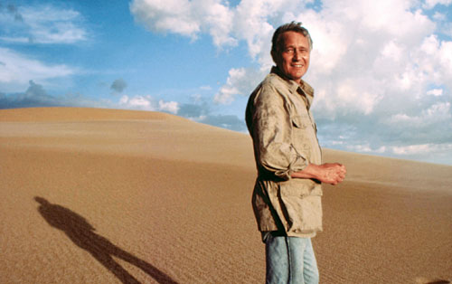 George Page on a sand dune with vast cloud-filled sky