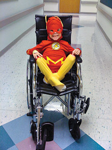 Child wearing superhero costume in wheelchair