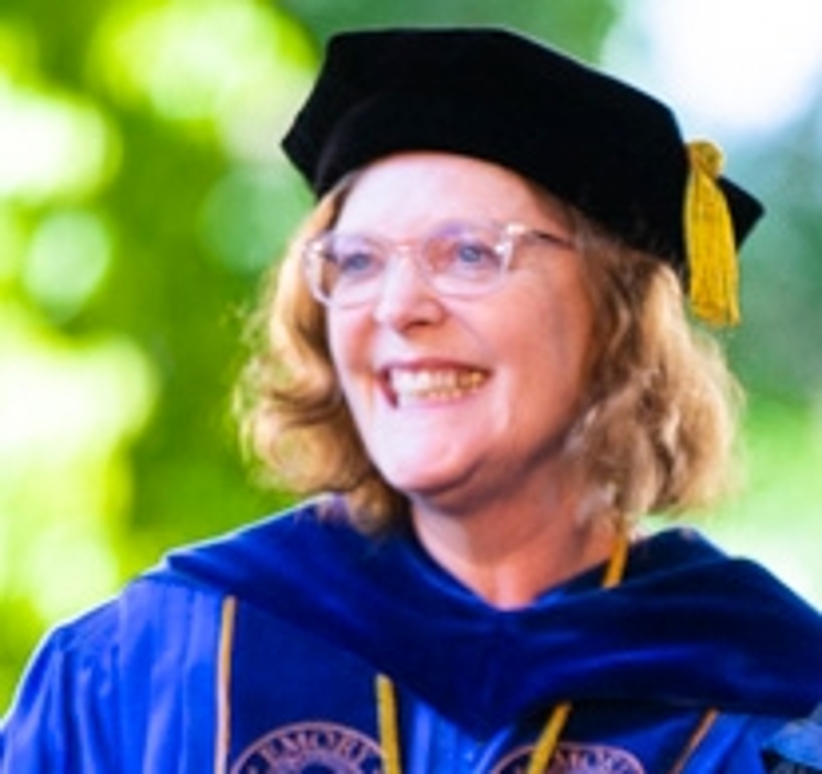 A candid portrait of Emory President Claire E. Sterk in commencement attire.