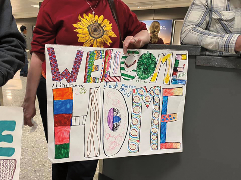 A sign on poster board; drawn in magic marker displays the words "welcome home" in childlike handwriting.