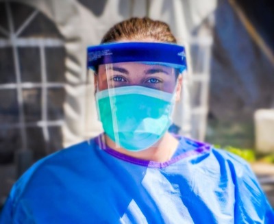 Photo of Kayla Lindros in blue Hospital scubas and full protective equipment including mask and face shield