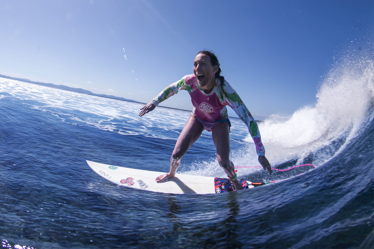 Photo of a person on a surfboard seeming to enjoy catching a wave.